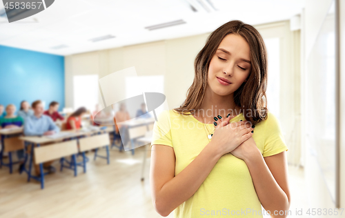 Image of student girl holding hands on heart at school