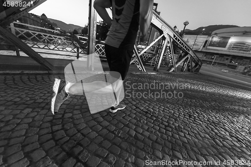 Image of man jogging across the bridge in the city