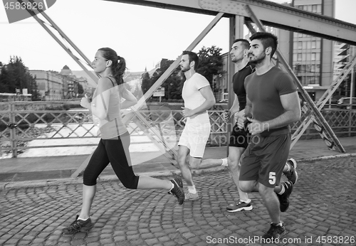 Image of group of young people jogging across the bridge