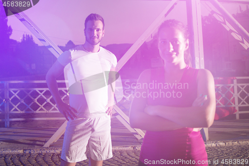 Image of portrait of couple jogging across the bridge in the city