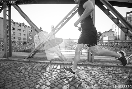 Image of man jogging across the bridge at sunny morning