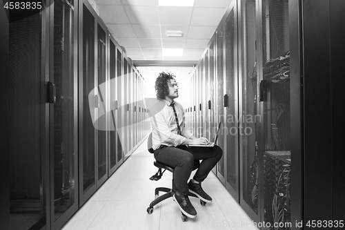 Image of engineer working on a laptop in server room