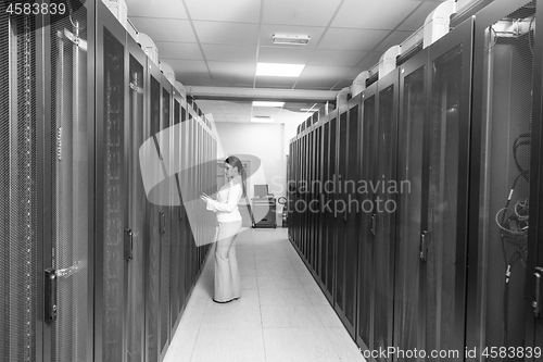 Image of Female engineer working on a tablet computer in server room