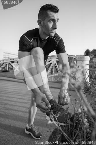 Image of man tying running shoes laces