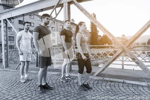 Image of group of young people jogging across the bridge