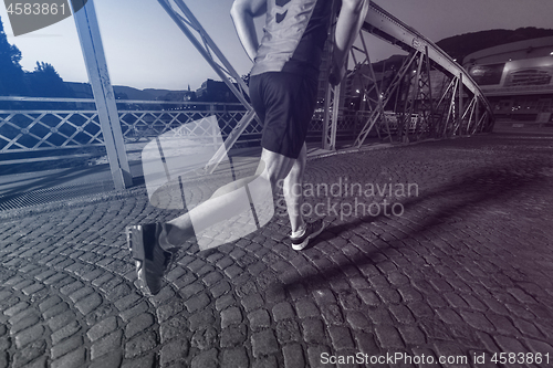 Image of man jogging across the bridge in the city