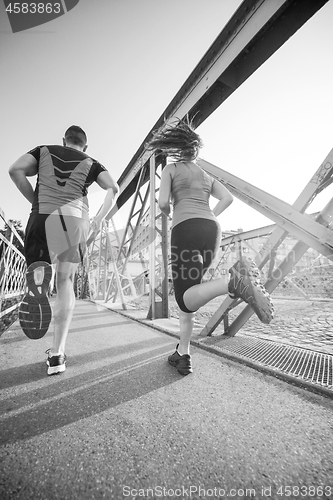 Image of young couple jogging across the bridge in the city