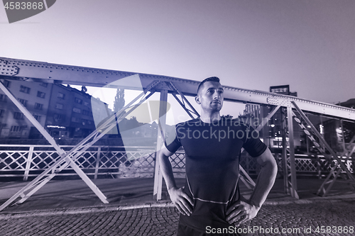 Image of man jogging across the bridge in the city