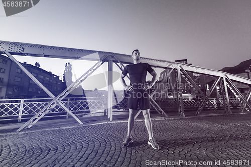 Image of man jogging across the bridge in the city