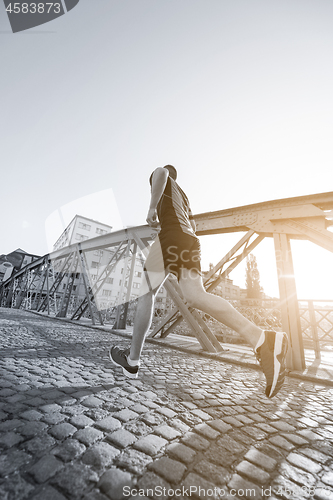 Image of man jogging across the bridge at sunny morning