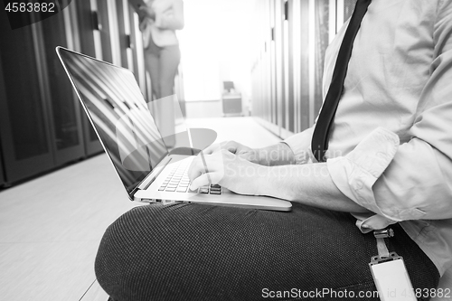 Image of engineer working on a laptop in server room