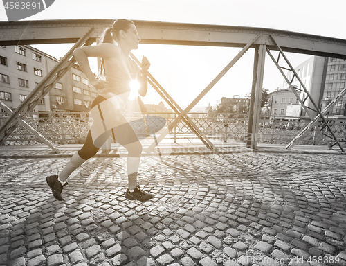 Image of woman jogging across the bridge at sunny morning