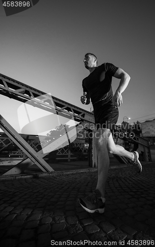 Image of man jogging across the bridge in the city