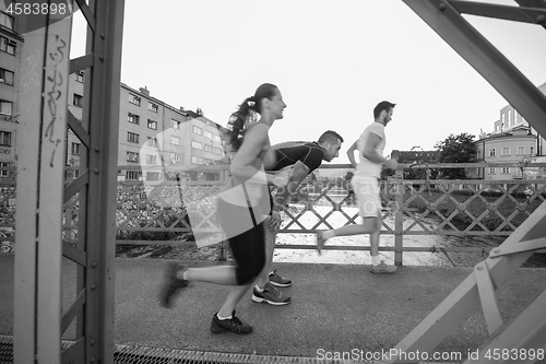 Image of young couple jogging across the bridge in the city