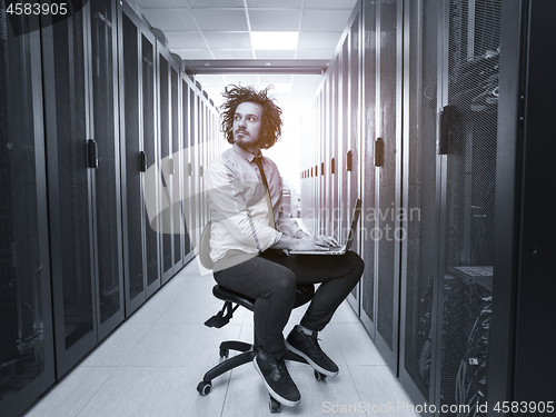 Image of engineer working on a laptop in server room