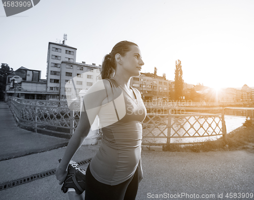 Image of woman jogging across the bridge at sunny morning