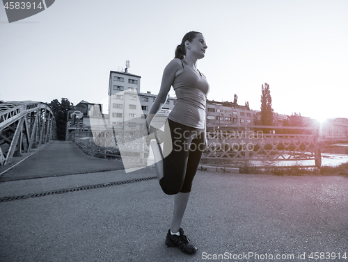 Image of woman jogging across the bridge at sunny morning