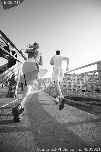 Image of young couple jogging across the bridge in the city