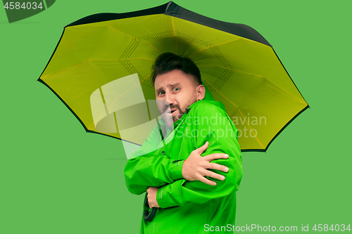 Image of handsome bearded young man holding umbrella and looking at camera isolated on white