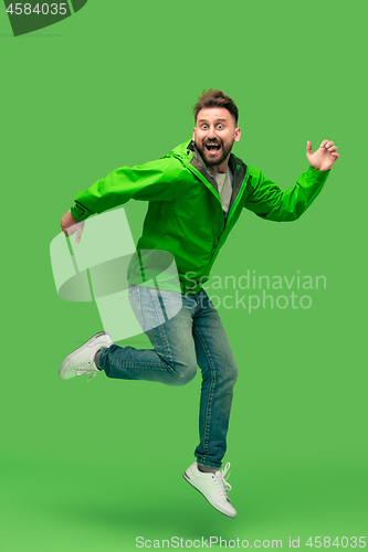 Image of handsome bearded young man running isolated on green