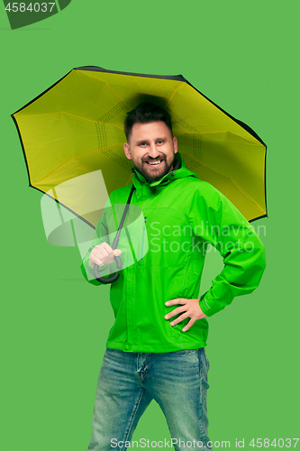 Image of handsome bearded young man holding umbrella and looking at camera isolated on white