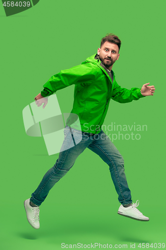 Image of handsome bearded young man running isolated on green