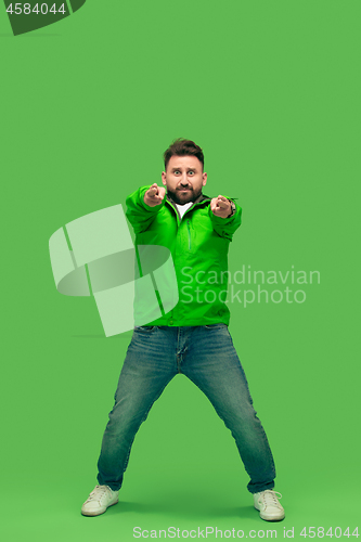 Image of handsome bearded young man looking at camera isolated on green