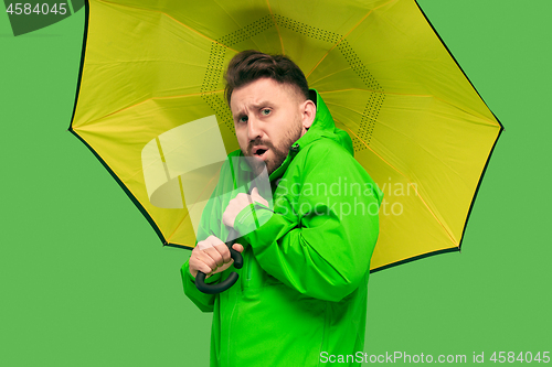 Image of handsome bearded young man holding umbrella and looking at camera isolated on white