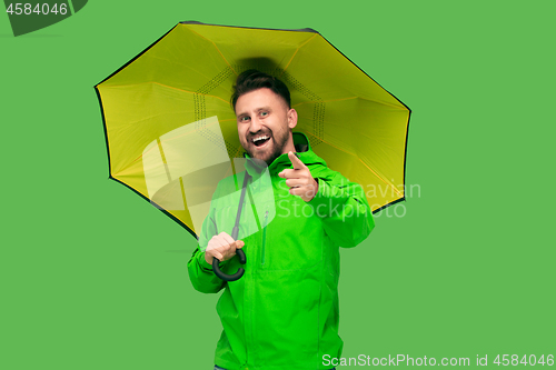 Image of handsome bearded young man holding umbrella and looking at camera isolated on white