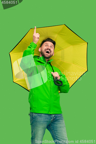 Image of handsome bearded young man holding umbrella and looking at camera isolated on white