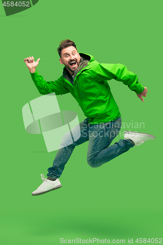 Image of handsome bearded young man running isolated on green