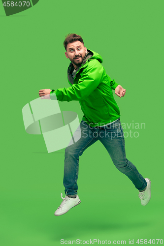 Image of handsome bearded young man running isolated on green