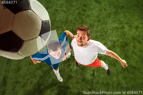 Image of Football players tackling for the ball over green grass background