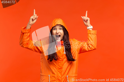 Image of The young girl posing at studio in autumn jacket isolated on red