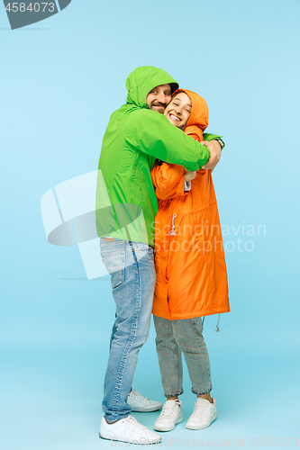 Image of The young surprised couplel posing at studio in autumn jackets isolated on blue