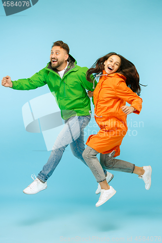 Image of The young surprised couplel posing at studio in autumn jackets isolated on blue