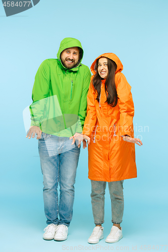 Image of The young couplel posing at studio in autumn jackets isolated on blue