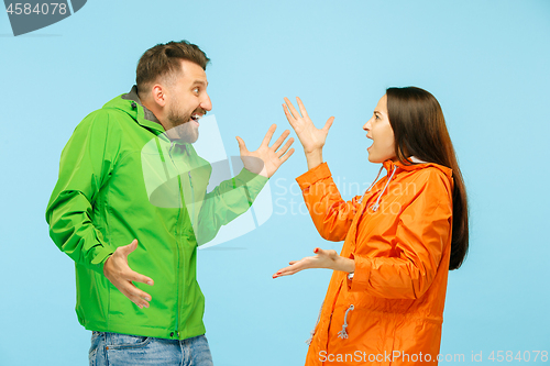 Image of The young surprised couplel posing at studio in autumn jackets isolated on blue