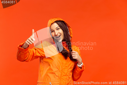 Image of The young girl posing at studio in autumn jacket isolated on red