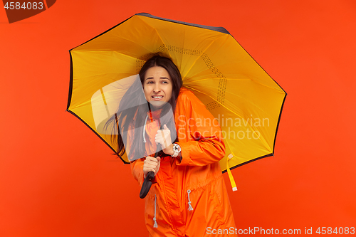 Image of The young girl posing at studio in autumn jacket isolated on red