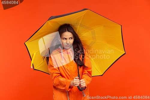 Image of The young girl posing at studio in autumn jacket isolated on red