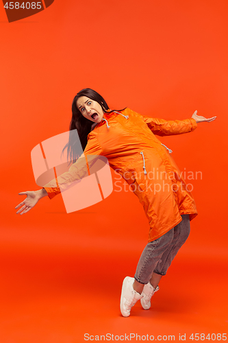 Image of The young girl posing at studio in autumn jacket isolated on red