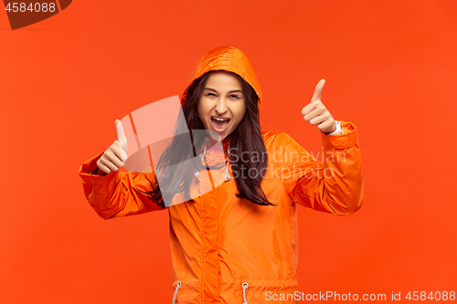 Image of The young girl posing at studio in autumn jacket isolated on red