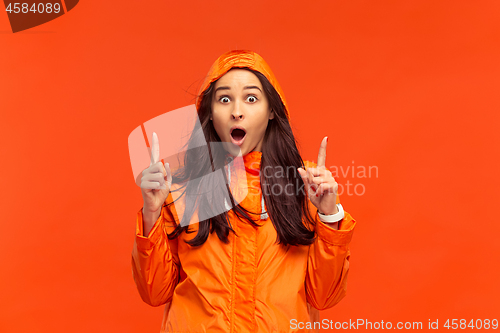 Image of The young girl posing at studio in autumn jacket isolated on red