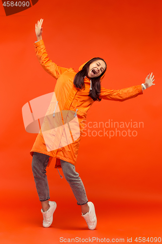 Image of The young girl posing at studio in autumn jacket isolated on red