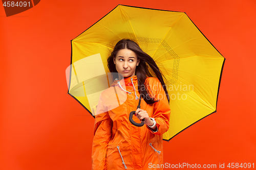 Image of The young girl posing at studio in autumn jacket isolated on red