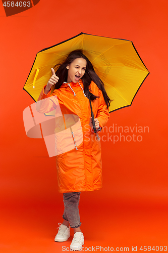 Image of The young girl posing at studio in autumn jacket isolated on red