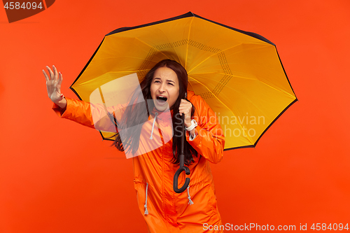 Image of The young girl posing at studio in autumn jacket isolated on red