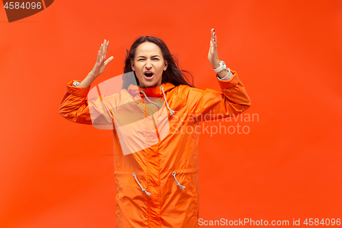 Image of The young girl posing at studio in autumn jacket isolated on red