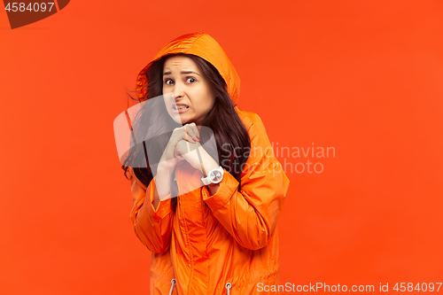 Image of The young girl posing at studio in autumn jacket isolated on red